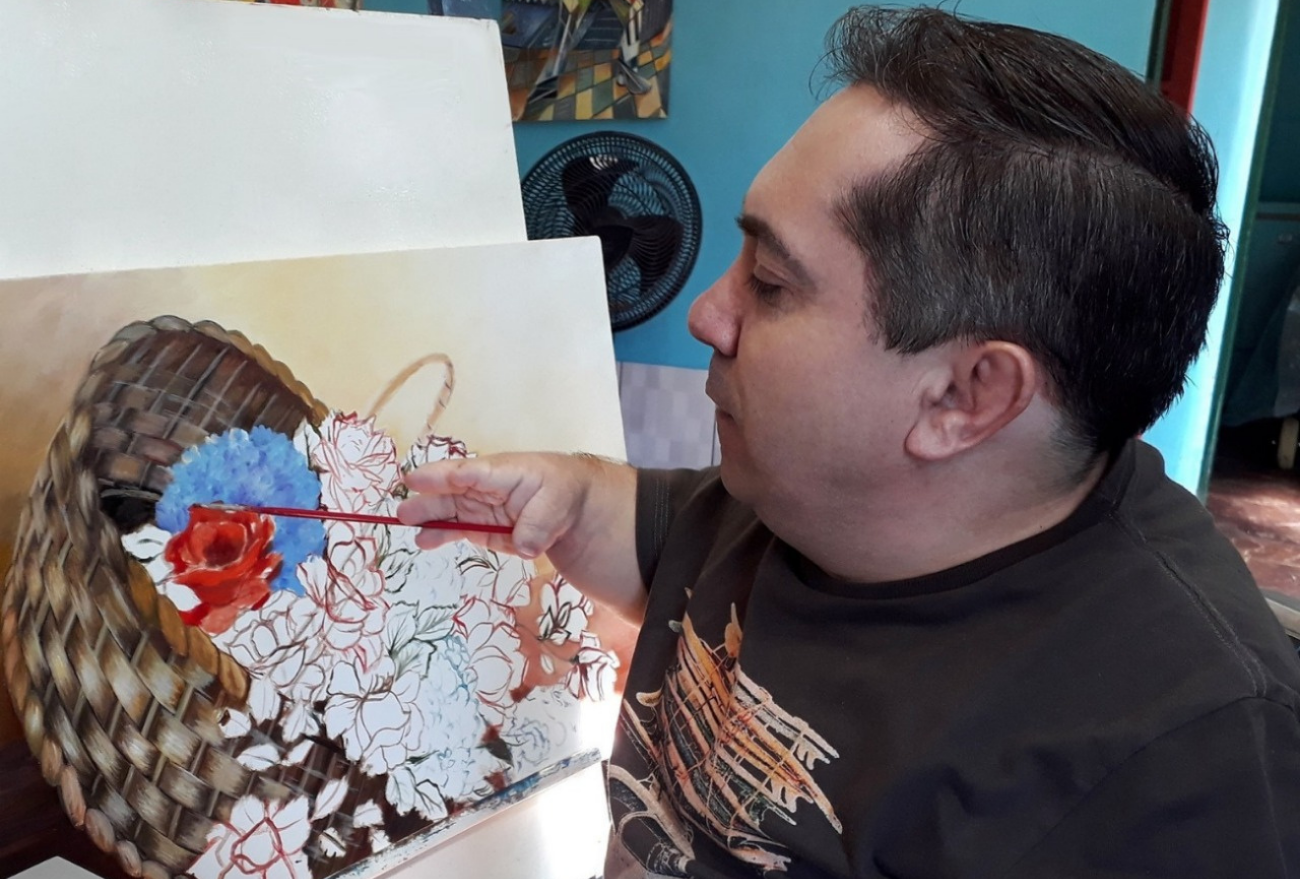 Pintor autodidata e com deficiência física faz sucesso com obras de arte